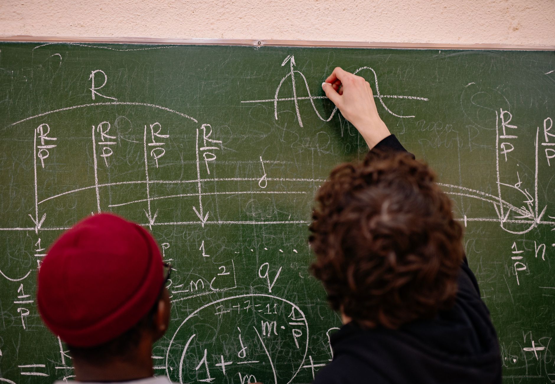 Students working together on complex math problems on a chalkboard.