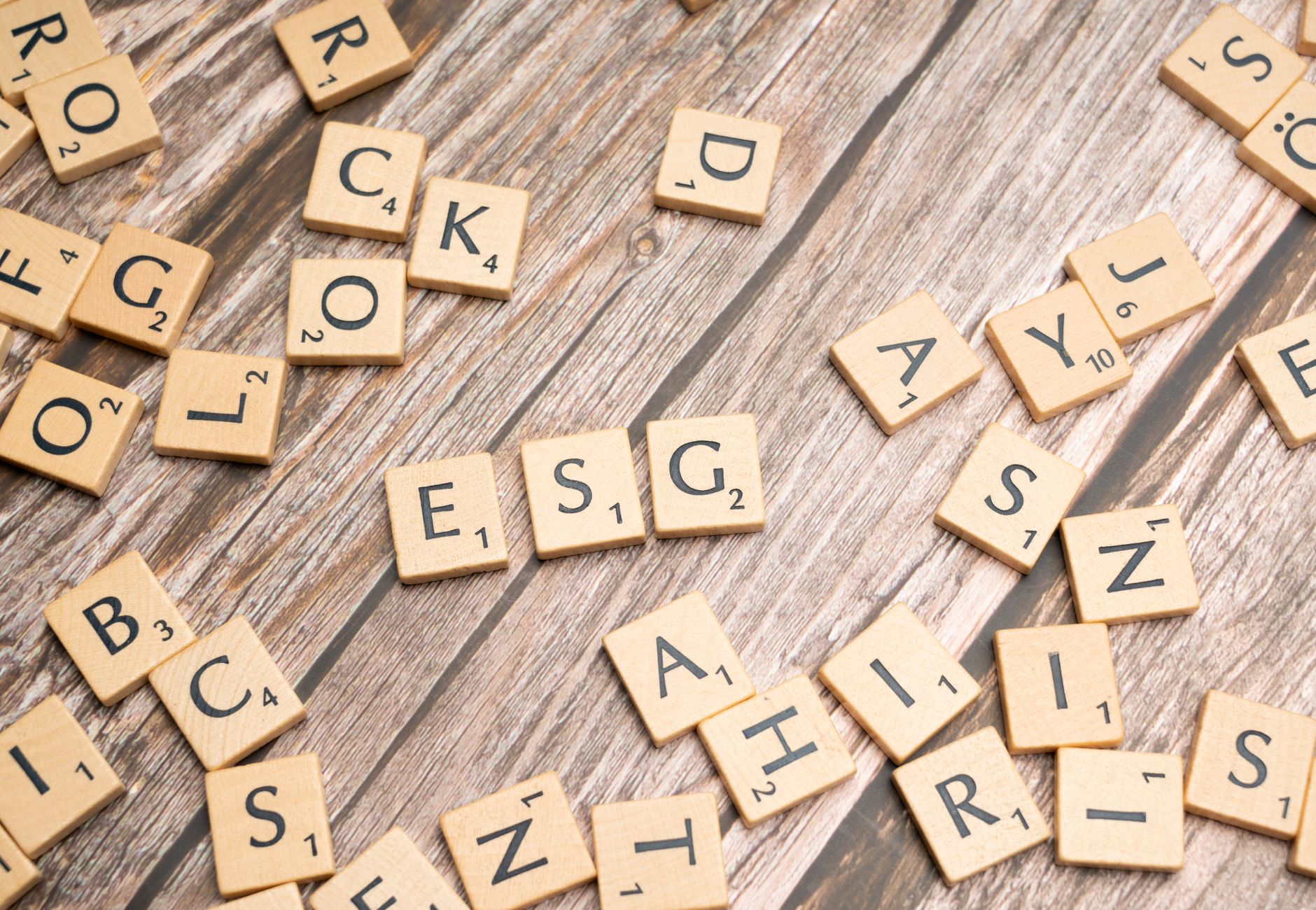 Wooden letter tiles spell ESG on a rustic wooden surface, emphasizing sustainability.