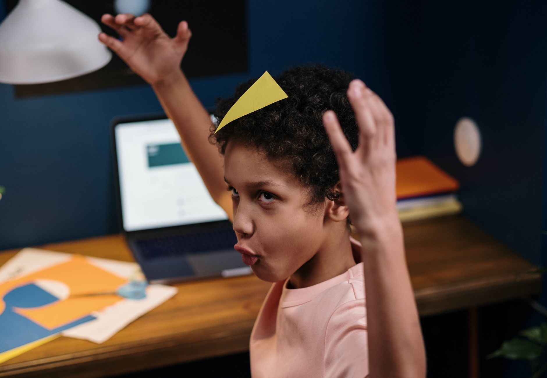 A playful child with afro hair enjoys a creative homeschooling session. Indoors setup.